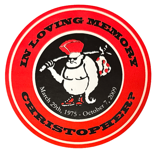 A round sticker with a clumsy logo in the middle of a neanderthal-monkey with a mohawk and a bindle. The text reads, "In Loving Memory, Christopher?, March 29th, 1975-October 7, 2009